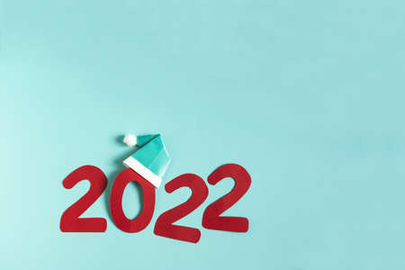 The number 2022 with a New Year's decoration in the form of a cap on a blue background is a place...