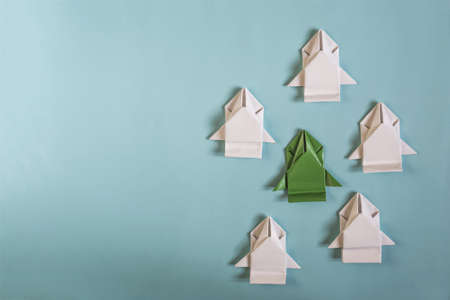 The concept of competition. A green paper car surrounded by white cars on a blue background is a place for textの写真素材