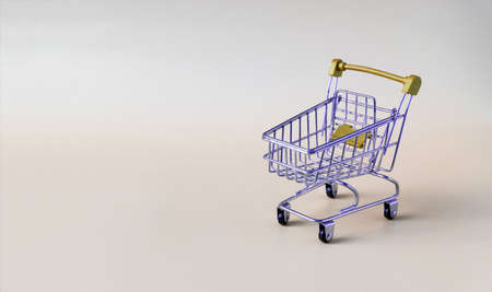 Yellow empty metal basket from a supermarket on a beige background close-up of a trading concept