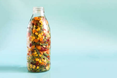 Frozen vegetables in a transparent bottle on a light background. The concept of fast-frozen foodの写真素材