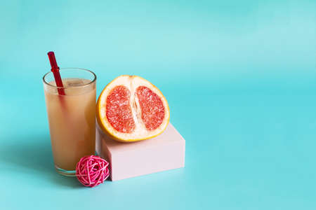 Grapefruit juice and a slice of grapefruit on a blue background. Grapefruit juice in a glass glass and decor on a colored background place for textの写真素材