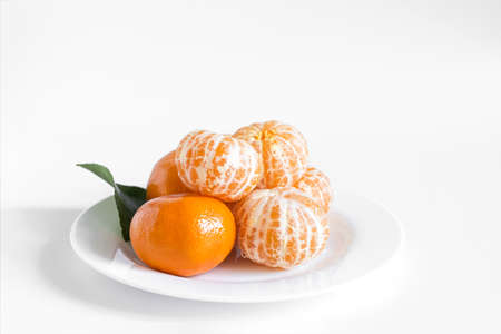 Fresh tangerines with a green leaf on a white plate close-upの写真素材