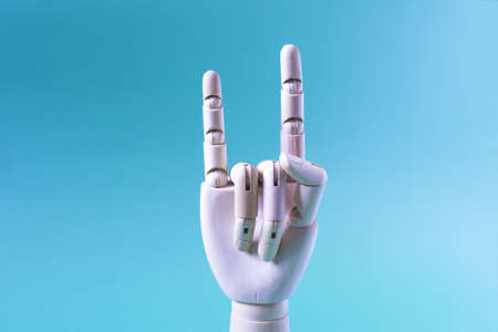 A conceptual hand gesture. A wooden hand with the index finger and little finger raised up on a blue background close-up.の写真素材