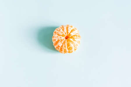 Concept bright peeled tangerine on a light blue background close-upの写真素材