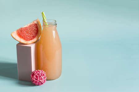 Grapefruit juice and grapefruit slices on a blue background. Grapefruit juice in a transparent...