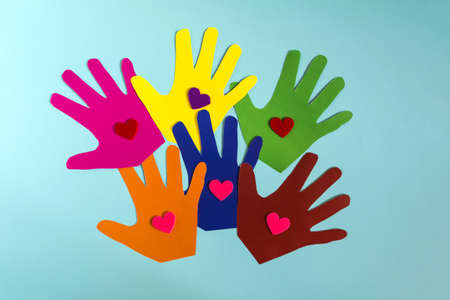 Abstract background colored paper children's palms with hearts on a colored background.