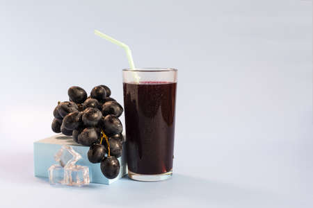 A vine and a glass of grape juice on a light background close-up.の写真素材