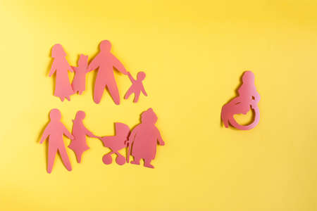The concept of the relationship of people and society to people with disabilities. Cardboard figures in red on a yellow background.の写真素材