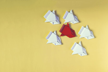 The concept of struggle and competition. A red origami car competes with white cars on a yellow backgroundの写真素材