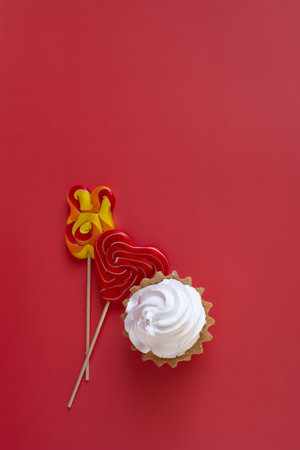 Two bright lollipops and an airy cake on a bright red background vertical orientation.の写真素材