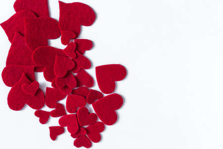 Background of a scattering of bright red fabric hearts on a white background is a place for text.の写真素材
