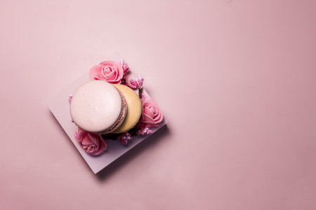 Flatlay macaroons with a decor in the form of pink flowers and a pink podium on a light pink background.の写真素材