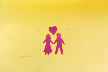 Figures of two people in a painted house on a yellow background.の写真素材