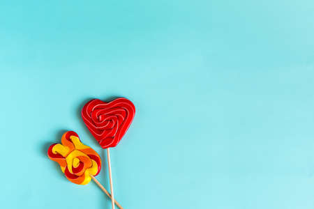 Two bright colored lollipops on sticks on a bright blue background is a place for text.