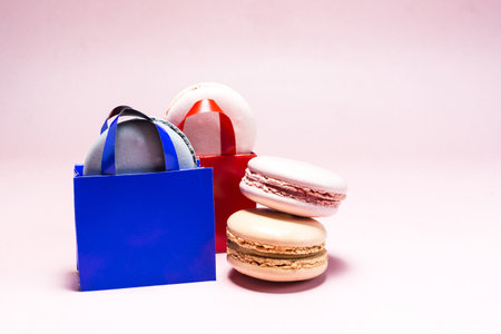 Sweet dessert colored macaroons in colored paper bags on a light background.の写真素材