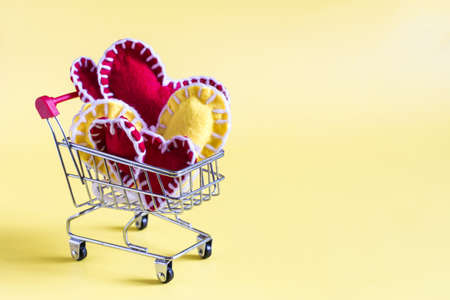 A grocery basket with colored soft hearts on a yellow background is a place for text.