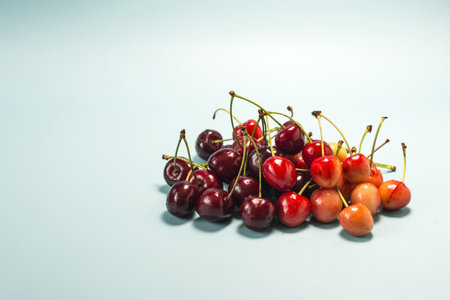 Ripe cherries of two types close-up on a blue background.の写真素材