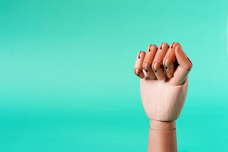 A wooden hand with clenched fingers in a fist on a light background. Conceptual hand gesture.の写真素材