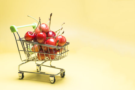 Grocery basket filled with ripe red cherries on a yellow background kopi spaceの写真素材