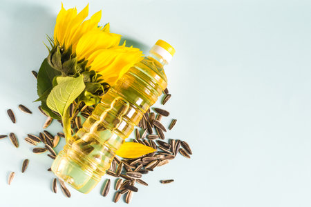 Sunflower oil in a transparent bottle sunflower seeds and sunflower flower close-up on a blue background copy spaceの写真素材