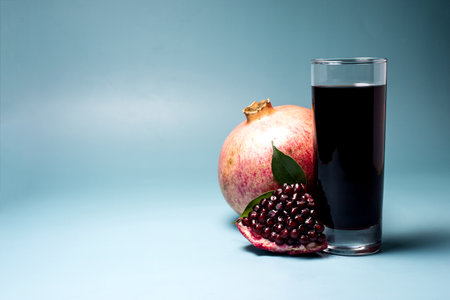 Pomegranate juice in a transparent glass and a pomegranate slice in close-up on a dark background.の写真素材