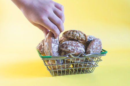 A hand takes a gingerbread from a basket full of fresh gingerbread beige backgroundの写真素材