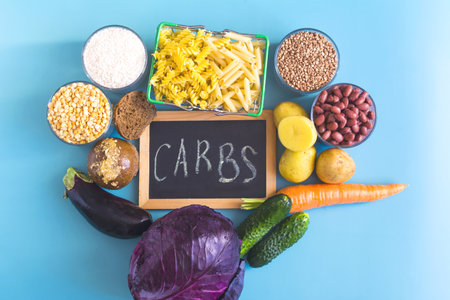 A set of foods containing complex carbohydrates, and the inscription on the âcarbohydratesâ sign in close-up.の写真素材