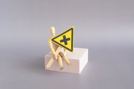 Warning sign "dangerous irritating substances", in the hands of a mannequin sitting on the podium, a light backgroundの写真素材