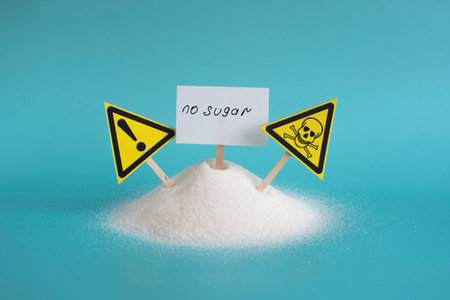 Warning about the dangers of sugar on the background of a mountain of granulated sugar and yellow warning signs on a light backgroundの写真素材