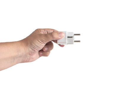 Hand holding out an electric plug, close-up on a white background, isolateの写真素材