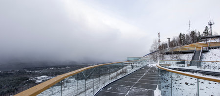 Panoramic view of the forest and the observation deck at the top of the mountain in winter on a gloomy day in bad weatherの写真素材