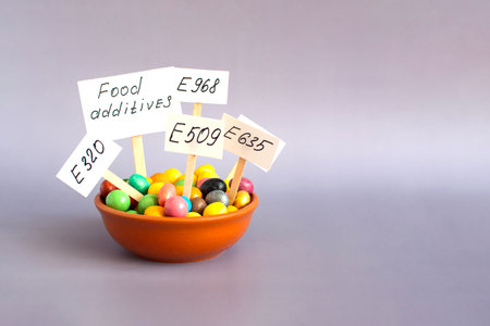 Pellets filled with various chemical food additives and information signs, close-up on a light background.の写真素材