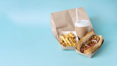 A banner with hot dog delivery products with sausage, French fries and a paper cup with a straw on a...
