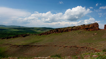 The banner features a beautiful panoramic view of green hills and red sandstone cliffs against a blue sky with cloudsの写真素材