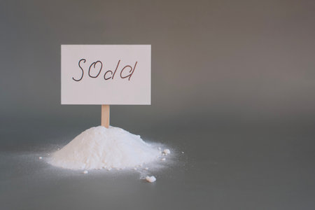 A slide of white baking soda and the inscription soda on the sign in close-up on a light background