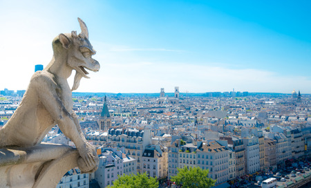Gargoyle (chimera) on Notre Dame de Paris close up overlooking blur city at a summer dayの写真素材