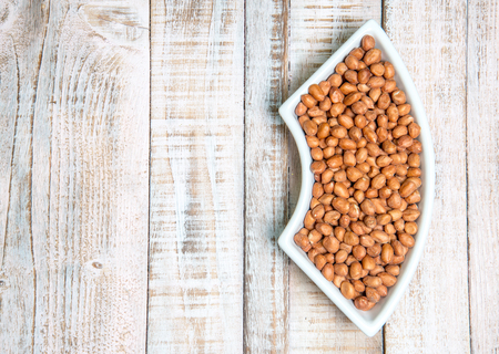 Peanut in a cup on a wooden background.
