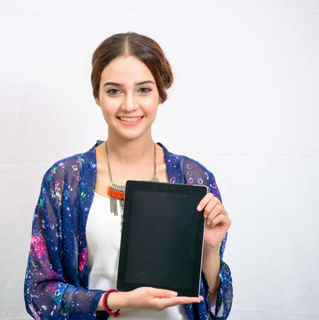 Beautiful young girl with tablet in studio white backgroundの写真素材