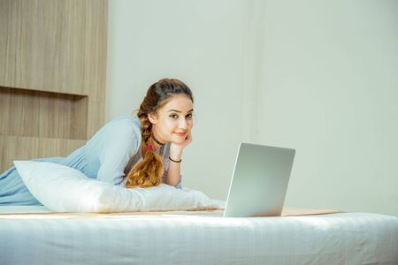 Beautiful young woman working on laptop in bed room