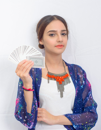 Beautiful young girl holding playing cards in hand
