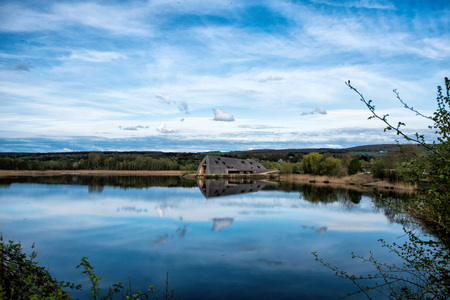 Remerschen, Luxembourg - April 15, 2018: Panoramic view of the lake in the nature reserve Haff Reimech and ornithology center Biodiversum in Remerschen near Schengen, Luxembourg.のeditorial素材