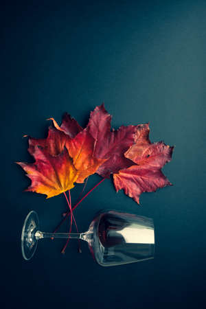 Wine glass with red wine and autumn grape leaves on black background. Creative wine degustation layout in rustic style, selective focus. Flat lay backdrop with copy space, top view.の写真素材