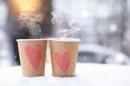 two craft cups of coffee with hearts standing on the snow on a winter day, it snows on February 14. High quality photoの写真素材