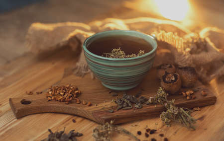 fragrant herbal tea in a cup, stands on a wooden surface next to dry herbs and berries. High quality photoの写真素材