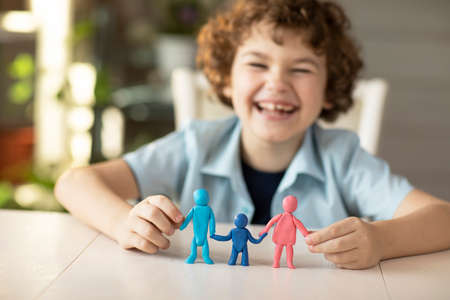 The boy made figures of people from plasticine dad, mother and child, happy smiles on camera, family relations conceptHigh quality photoの写真素材