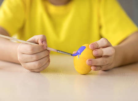 Boy decorates Easter egg, close-up