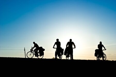 Group of Bicycle tourists on a road against sunsetの写真素材