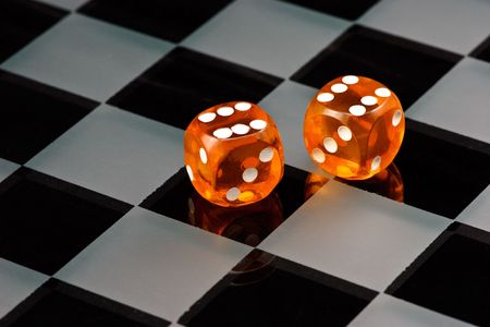 Two cube amber dice with rounded corners on checkered boardの写真素材