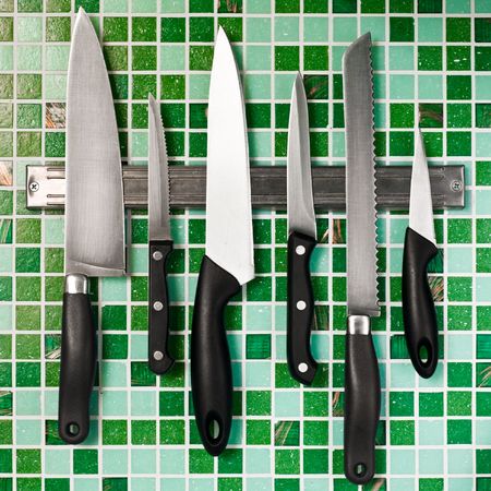 Kitchen knives on green mosaic wallの写真素材