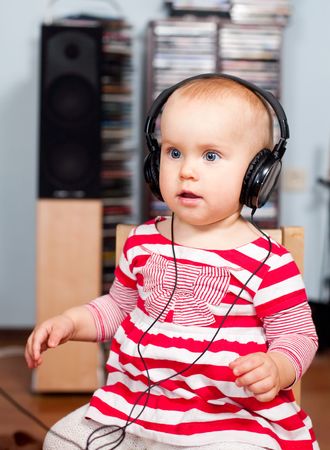 Cute little baby girl listening to a musicの写真素材